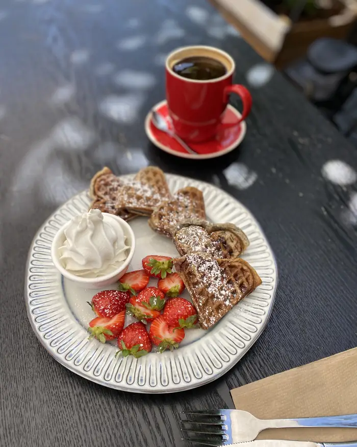 Coconut Pandan Waffles with strawberries and a coffee