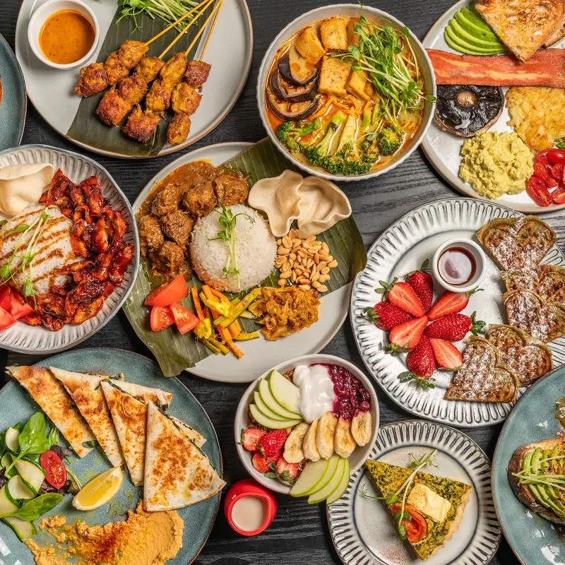 Satay sticks, nasi lemak, laksa, pandan waffles, gozleme and avocado toast from Loving Hut Perth on a dark wooden table
